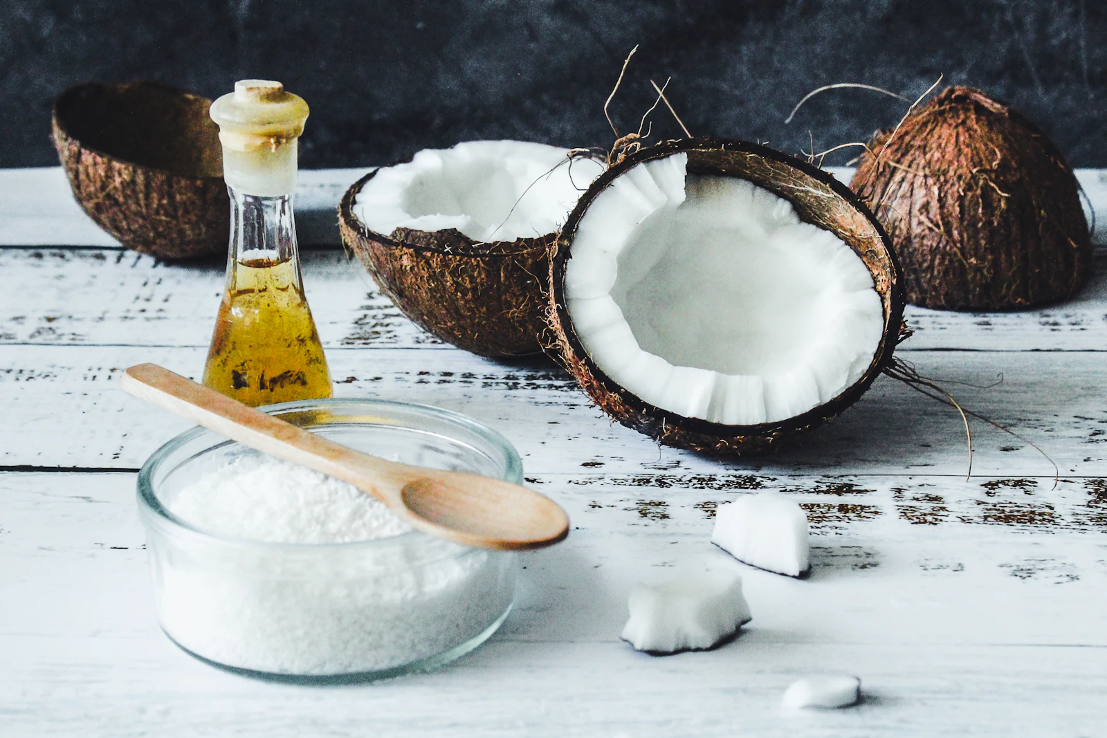 Coconut oil in a glass bottle beside coconut flesh